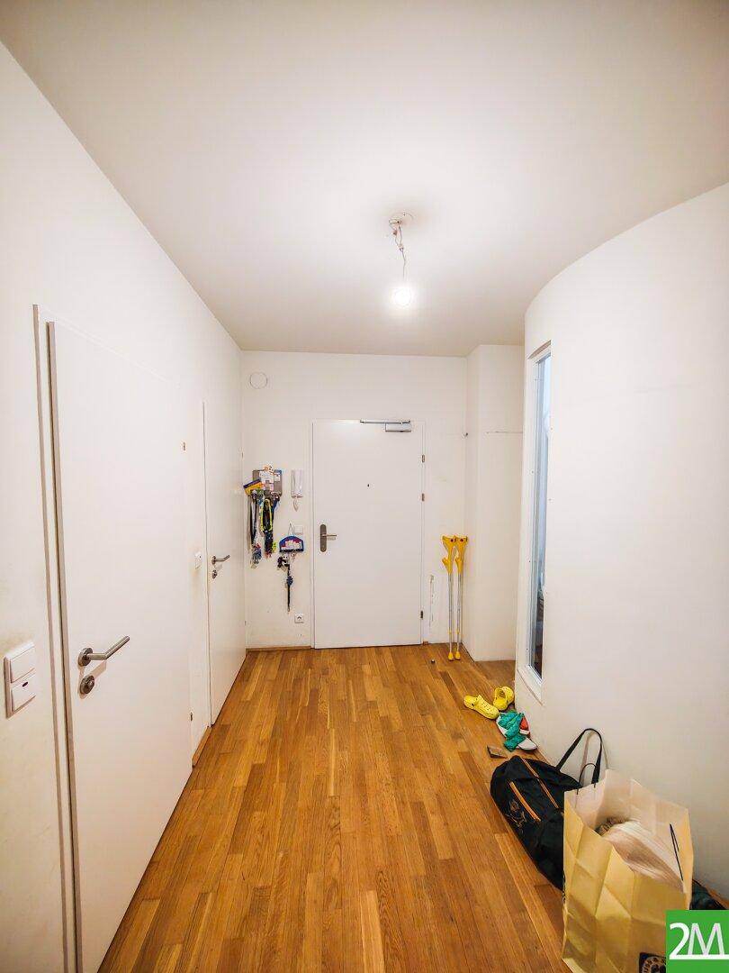 Heller Flur mit Holzboden und weißen Wänden, bietet Zugang zu den verschiedenen Räumen.