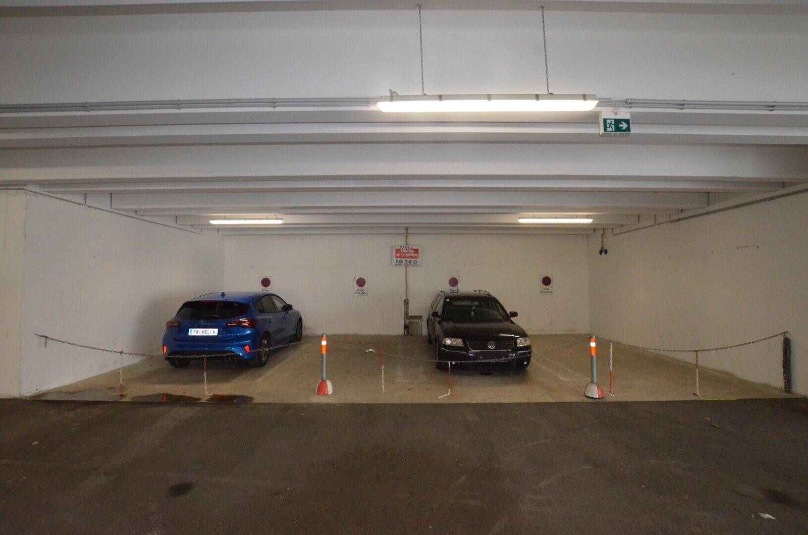 Heller Garagenbereich mit zwei Stellplätzen und einfacher Beleuchtung.