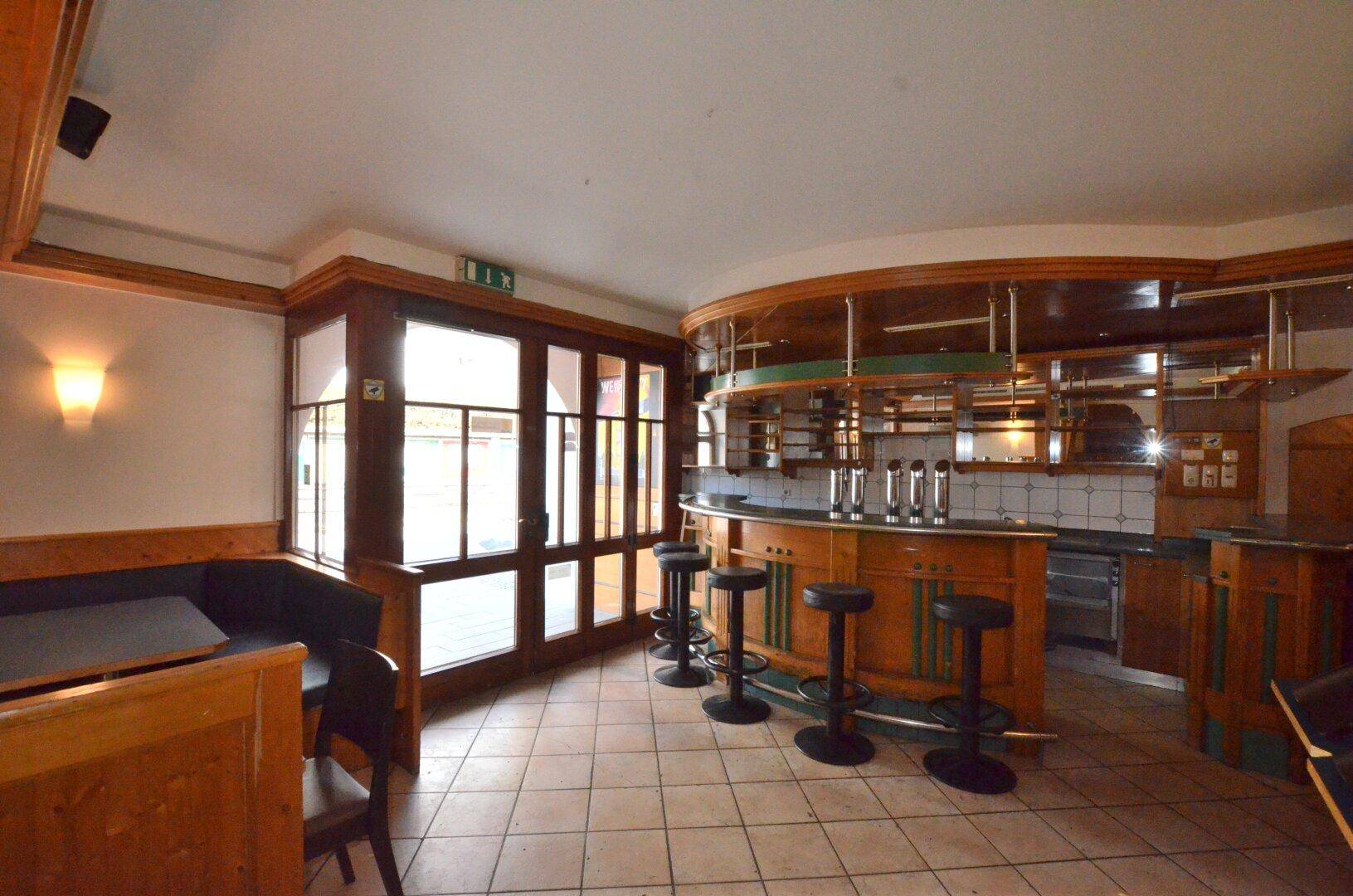 Gemütlicher Barbereich mit Holzinterieur, Sitzgelegenheiten und großen Fenstern.