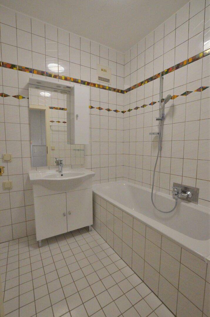 Gefliestes Badezimmer mit Badewanne, Waschbecken und Spiegelschrank.