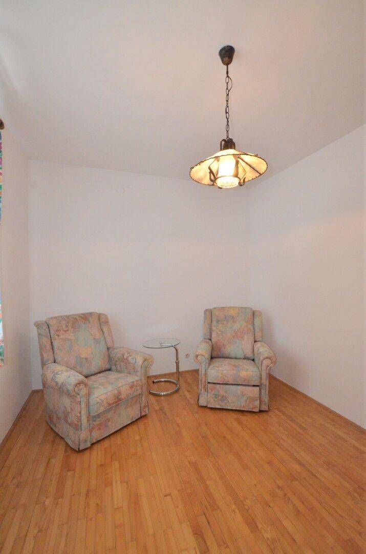 Helles Wohnzimmer mit Holzboden und zwei bequemen Polstersesseln, ideal zum Entspannen.
