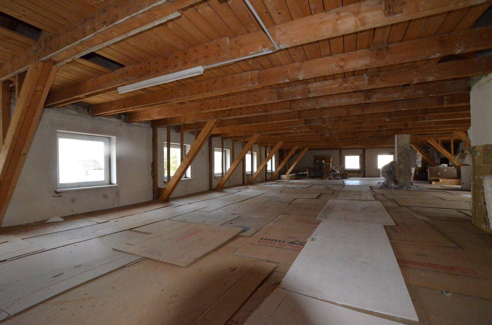 Großer, unfertiger Dachboden mit sichtbaren Holzbalken und Dachkonstruktion, bereit zum Ausbau.