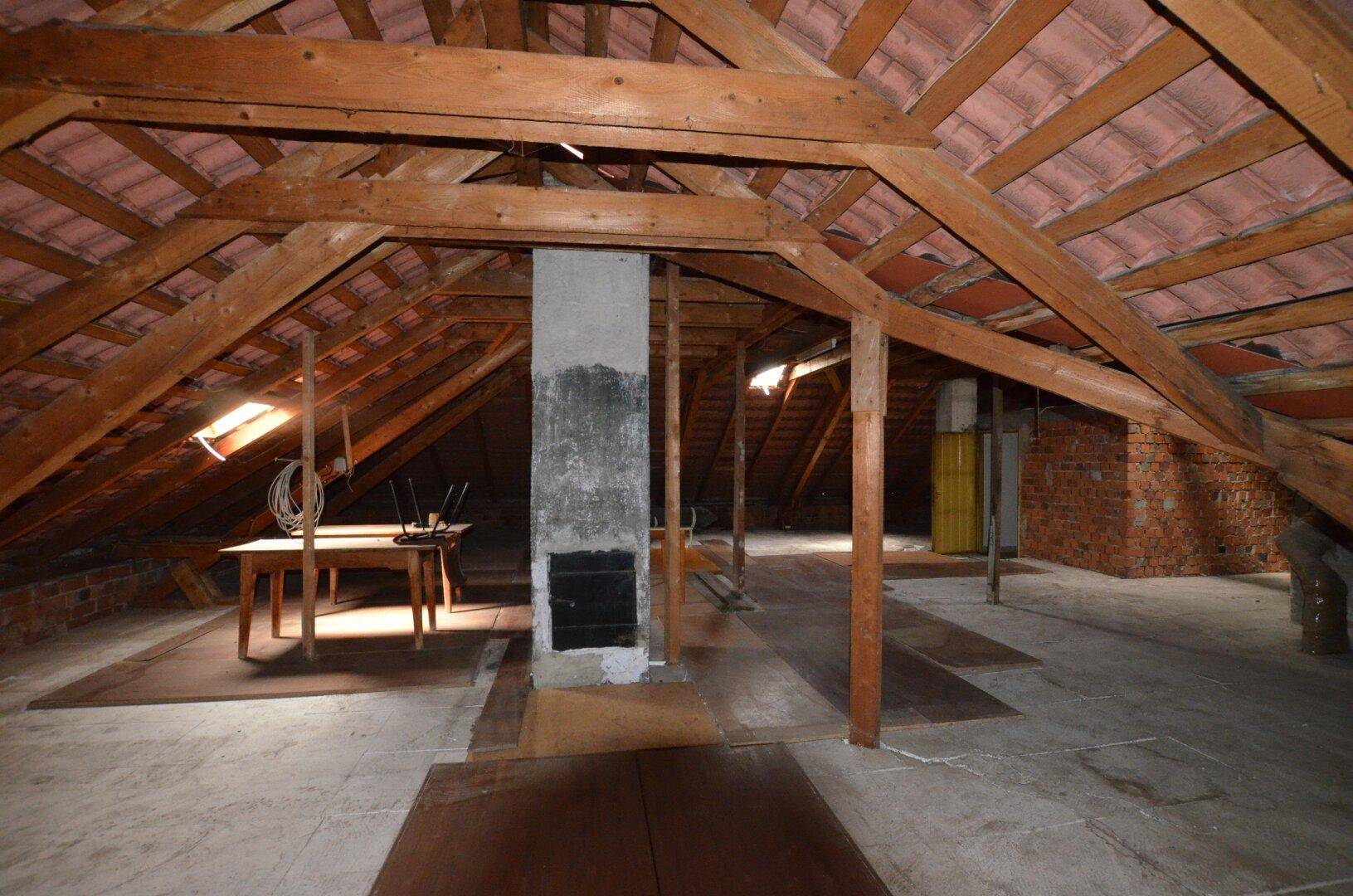 Großer Dachboden mit freiliegenden Holzbalken und Kamin, bietet viel Raum für individuelle Gestaltung.