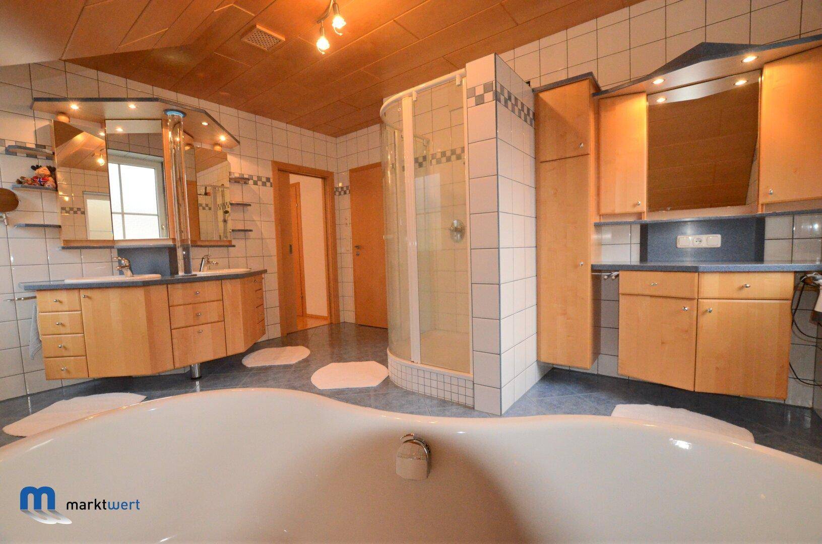 Großes Badezimmer mit Badewanne, Duschkabine, Doppelwaschbecken und Holzdecke.