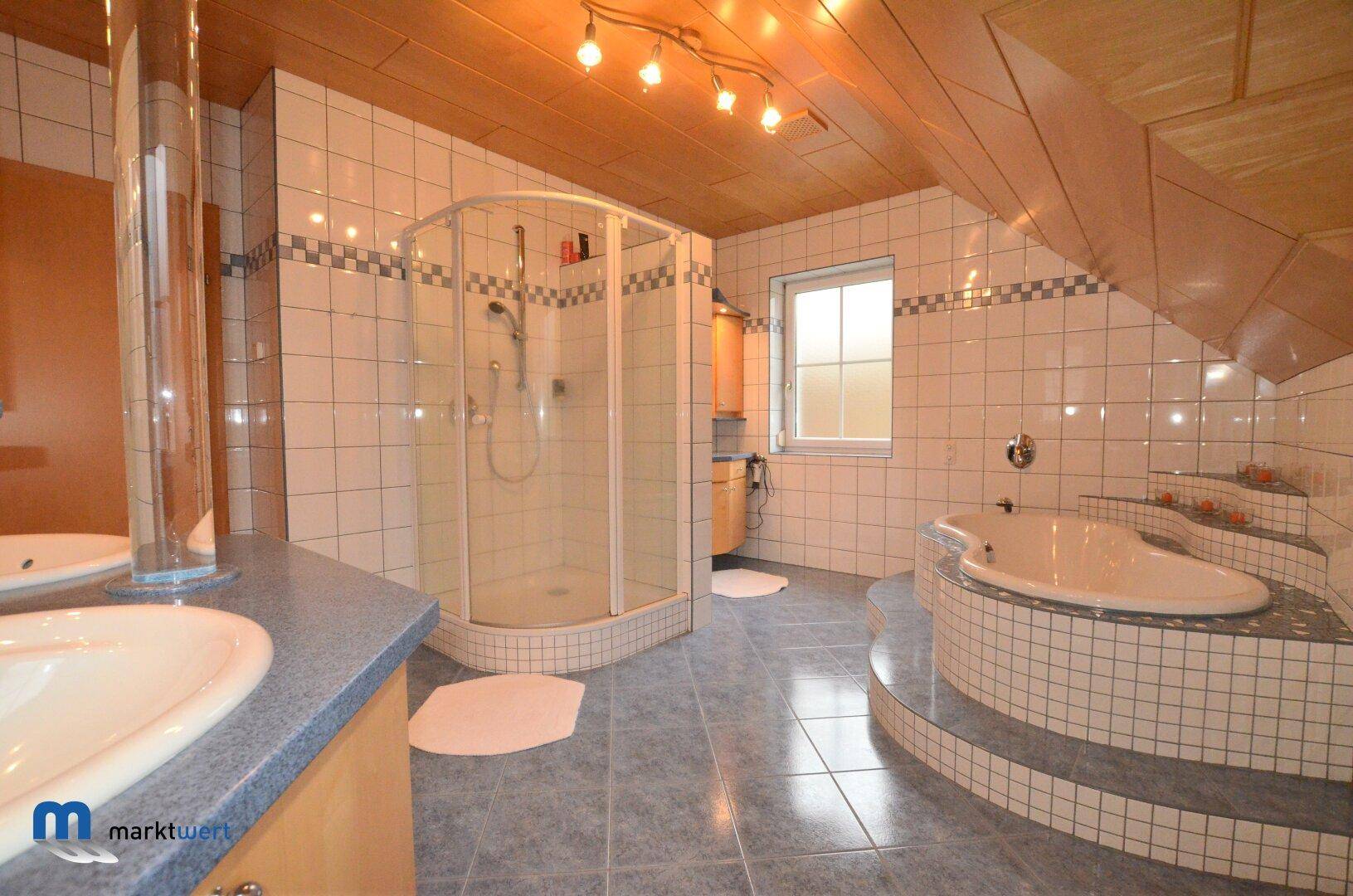 Geräumiges Badezimmer mit blauen Fliesen, Holzdecke, Eckbadewanne und Duschkabine.