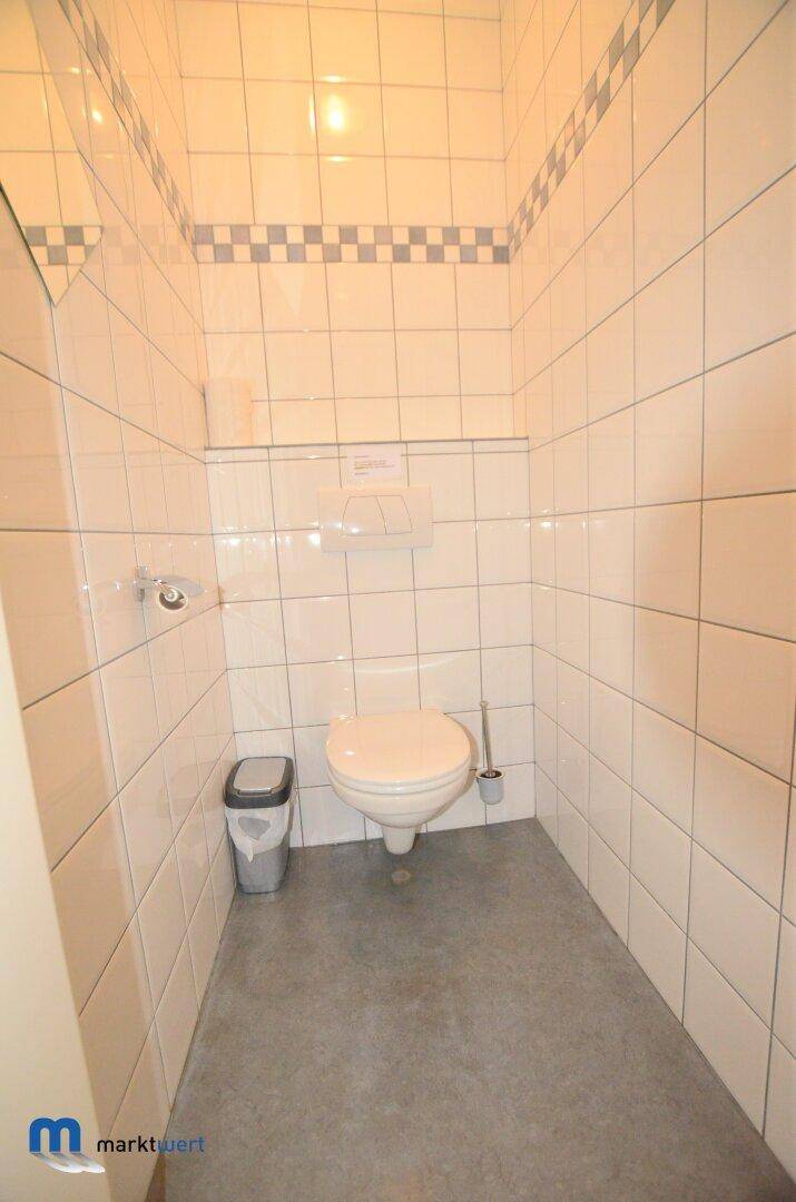 Kleiner Toilettenraum mit weißen Fliesen, einem Wand-WC und schlichtem Design.