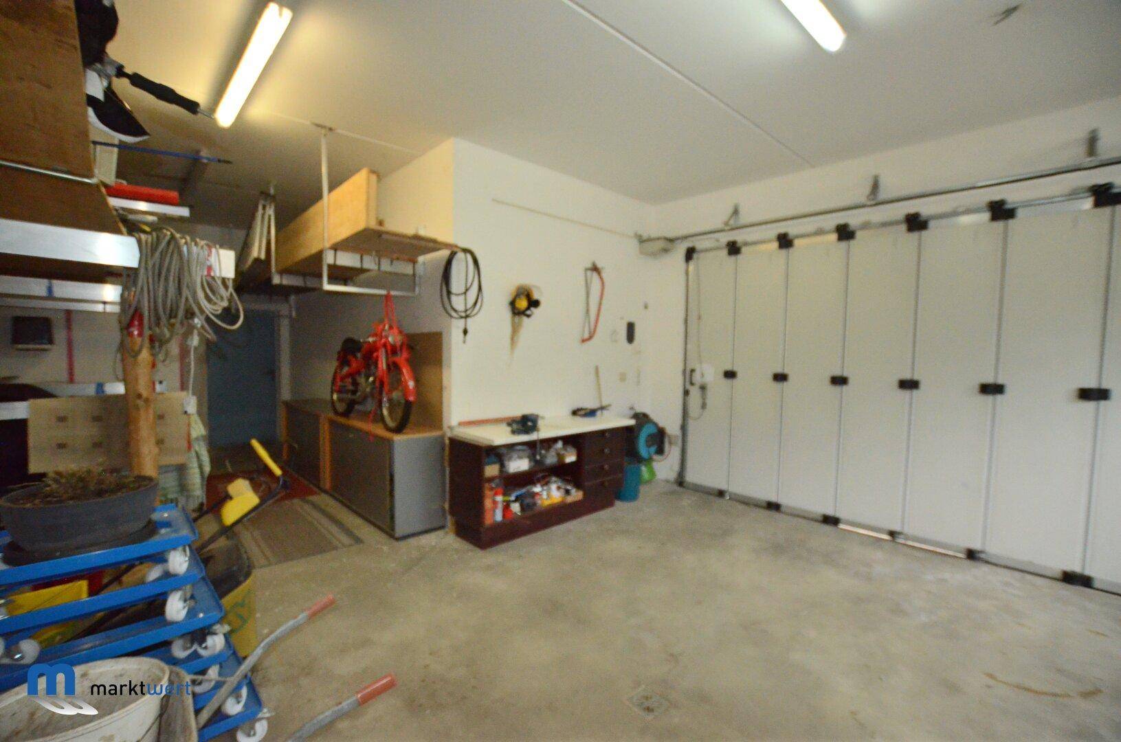 Weitläufige Garage mit Sektionaltor, viel Stauraum und Arbeitsfläche.