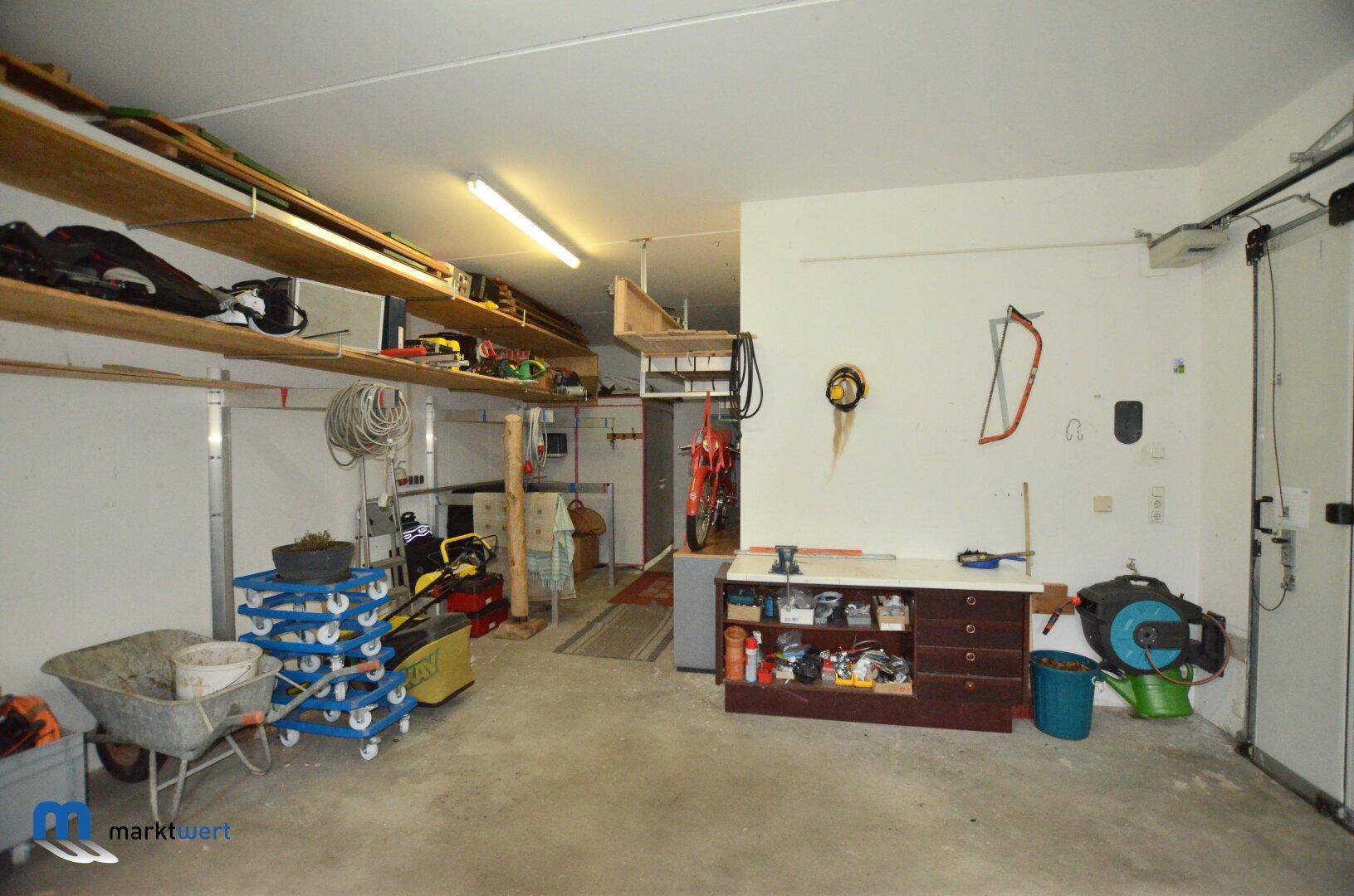Große Garage mit Werkzeugen, Regalen und Stauraum für verschiedene Geräte.