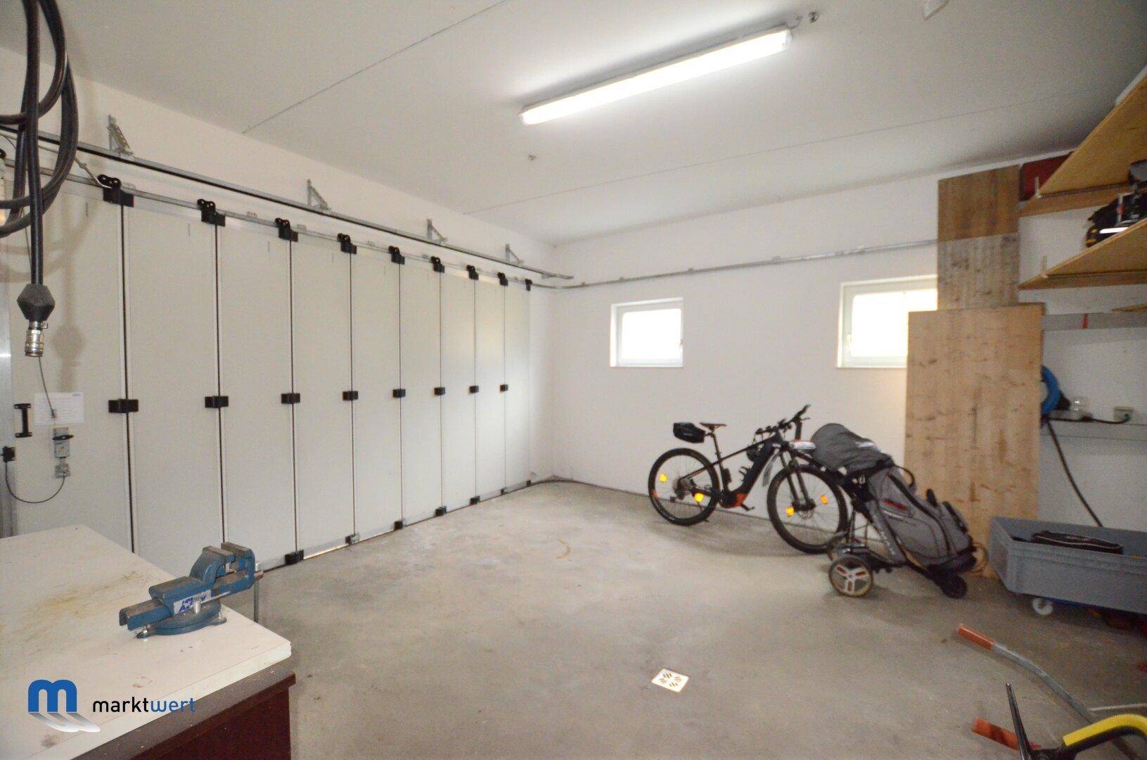 Geräumige Garage mit Fahrrad, Golfausrüstung und einer Werkbank.