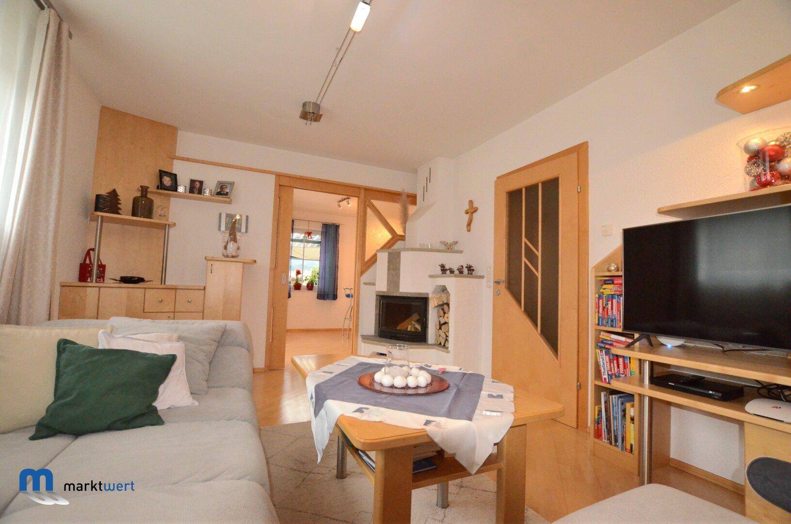 Gemütliches Wohnzimmer mit Kamin, Sofa und hellem Holzfußboden.