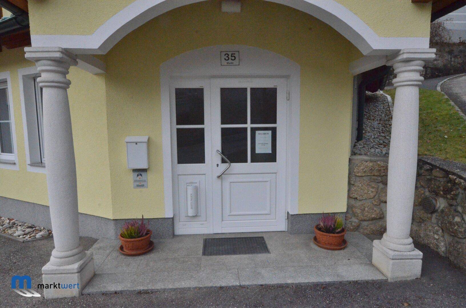 Eingangsbereich des Gebäudes mit weißen Säulen, Haustür und der Hausnummer 35.