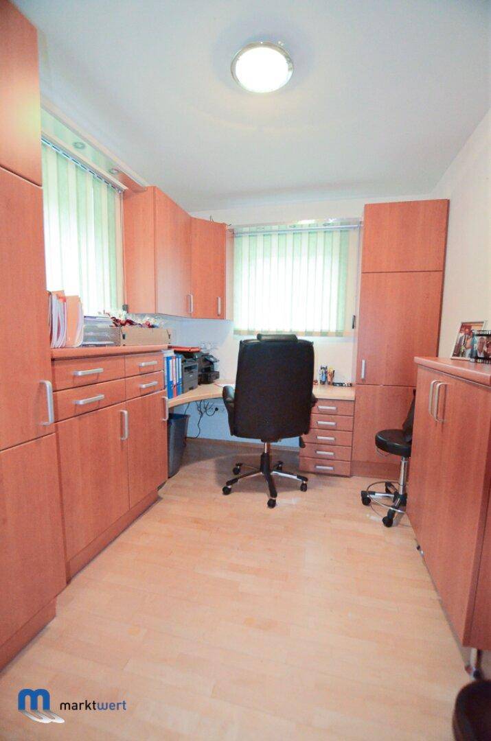 Funktionales Büro mit zahlreichen Holzschränken, Schreibtisch und Bürostuhl.