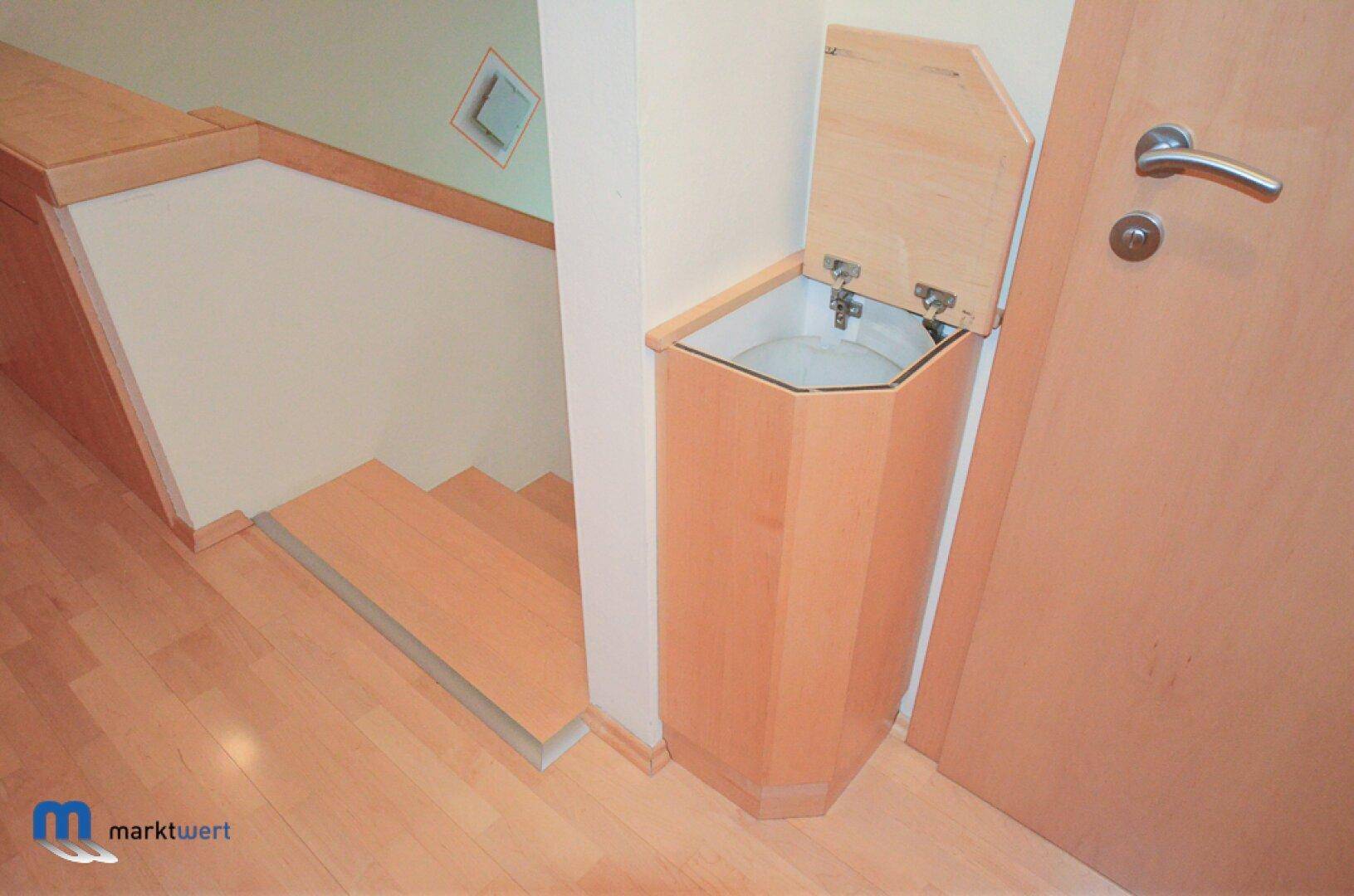 Heller Flur mit Holztreppe und praktischem Einbauschrank oder Wäscheschacht.