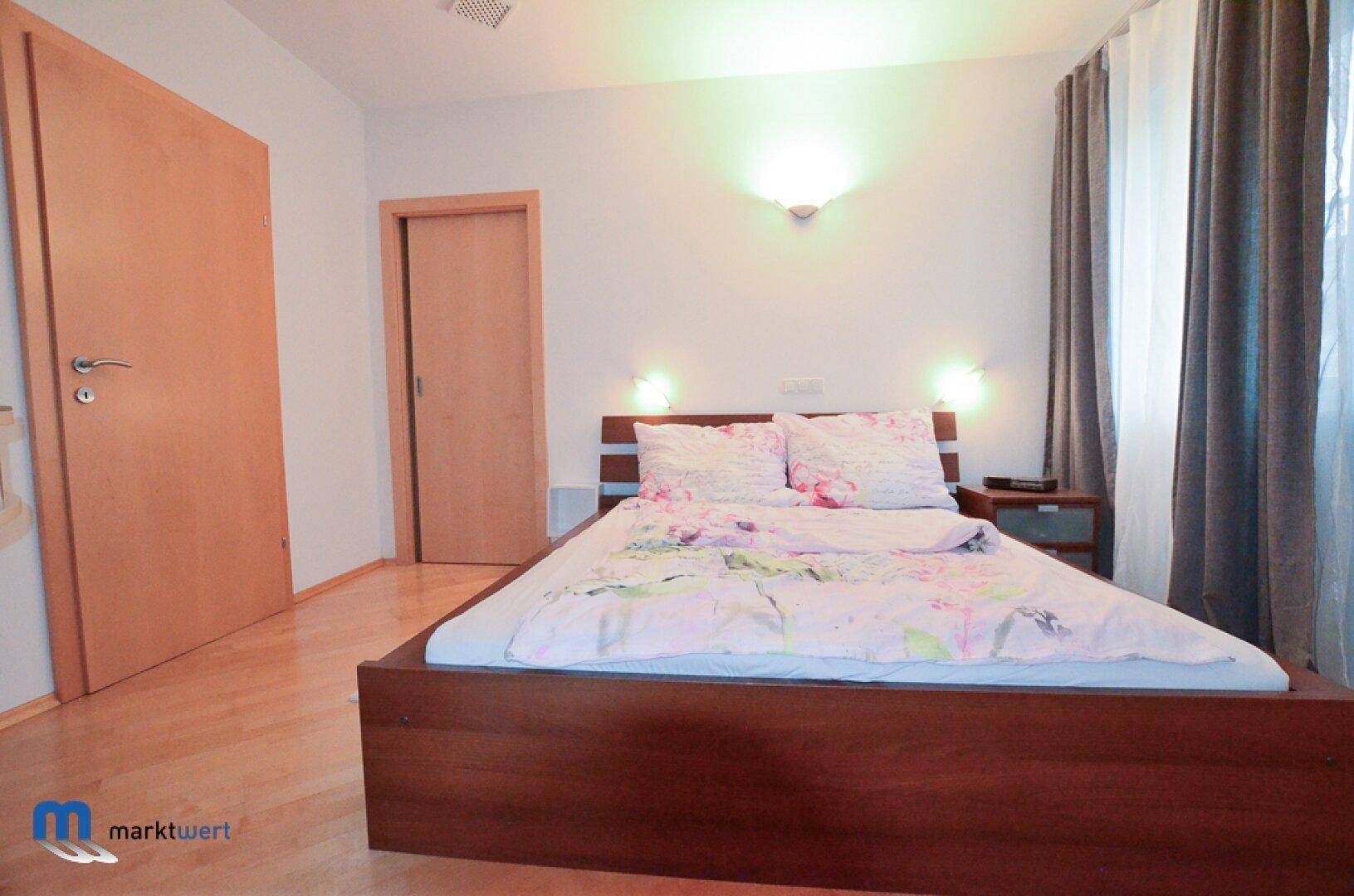 Gemütliches Schlafzimmer mit Doppelbett, Holzboden und schlichten Wänden.