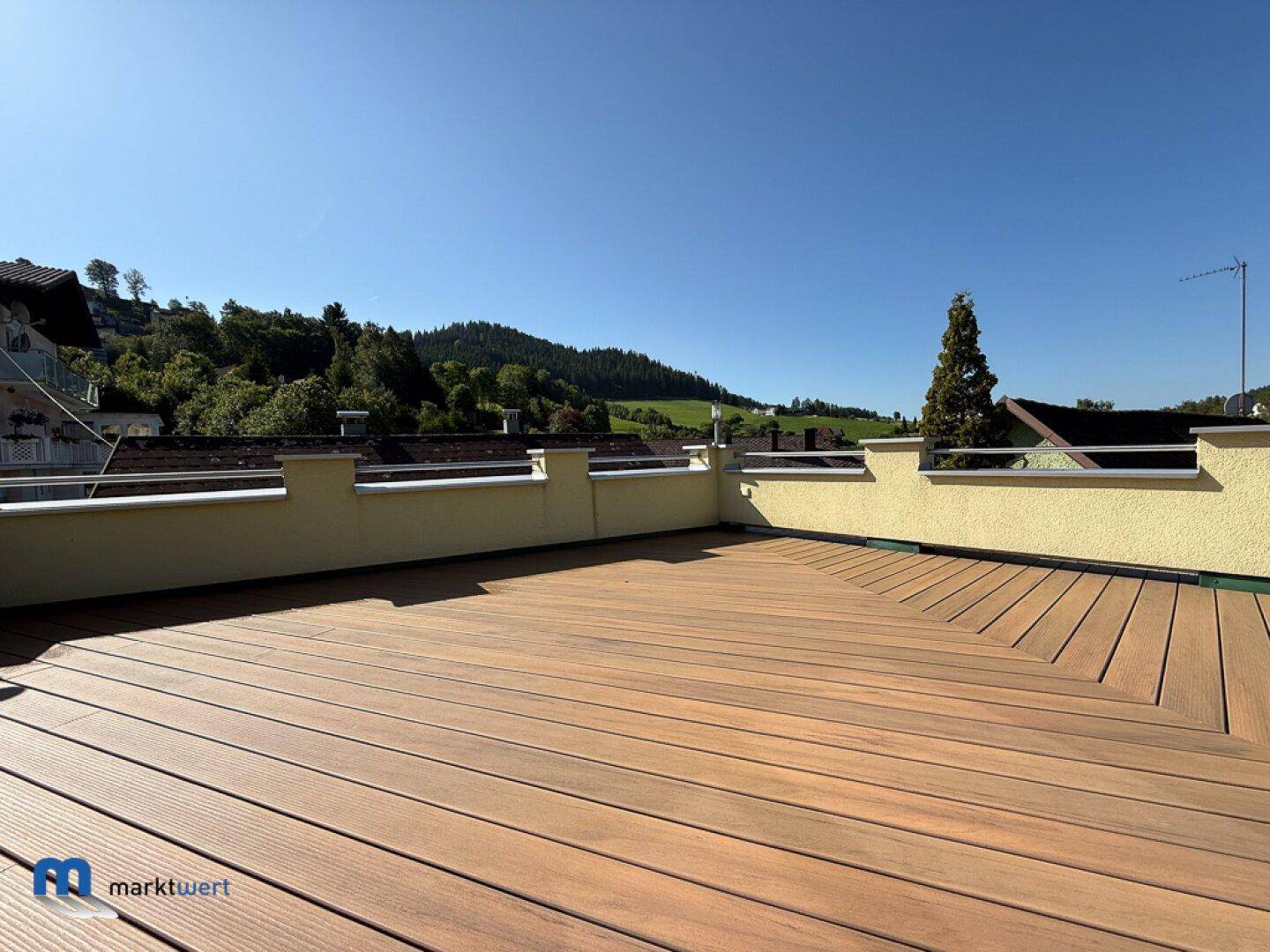 Geräumige Dachterrasse mit Holzdielenboden und weitem Blick auf die umliegende Landschaft.