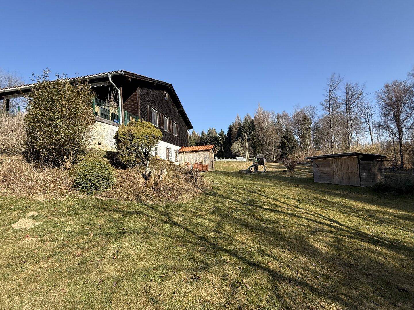 Weitläufige Rasenfläche vor dem Haus mit altem Baumbestand und viel Grün.