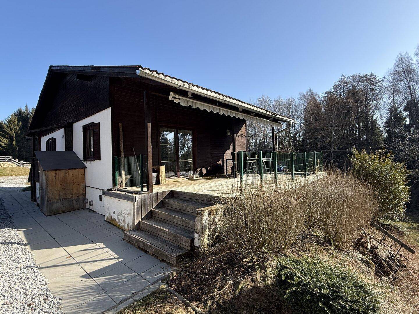 Rückseite des Hauses mit großer Holzterrasse und Zugang zum Gartenbereich.