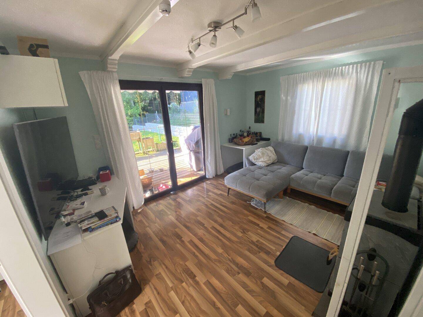 Gemütliches Wohnzimmer mit Sofa, Holzboden und direktem Zugang zur Terrasse.