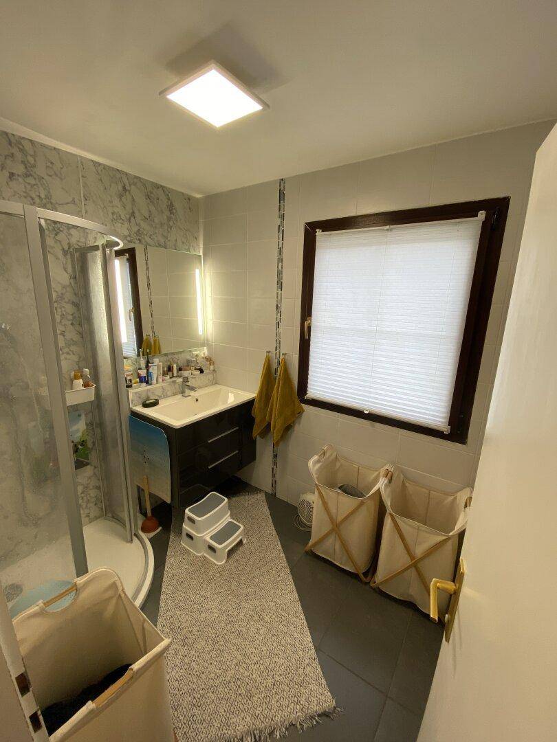 Modernes Badezimmer mit Duschkabine, Waschbecken und Fenster für Tageslicht.