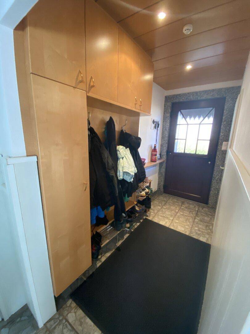 Eingangsbereich mit Garderobe, Fliesenboden und Holztäfelung an der Decke.