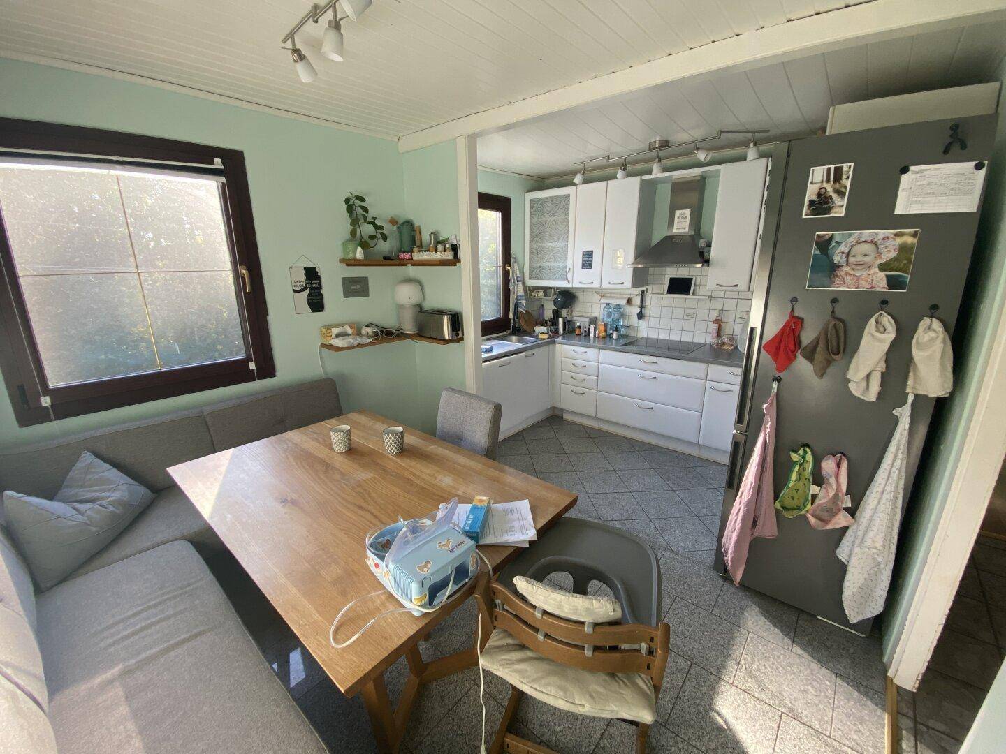 Helle Küche mit Essbereich, weißen Schränken, großem Fenster und viel Tageslicht.