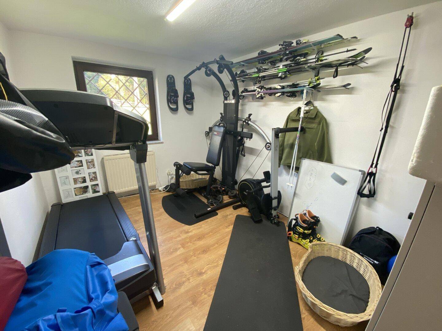 Raum eingerichtet als Fitnessbereich mit Trainingsgeräten und Stauraum für Sportausrüstung.