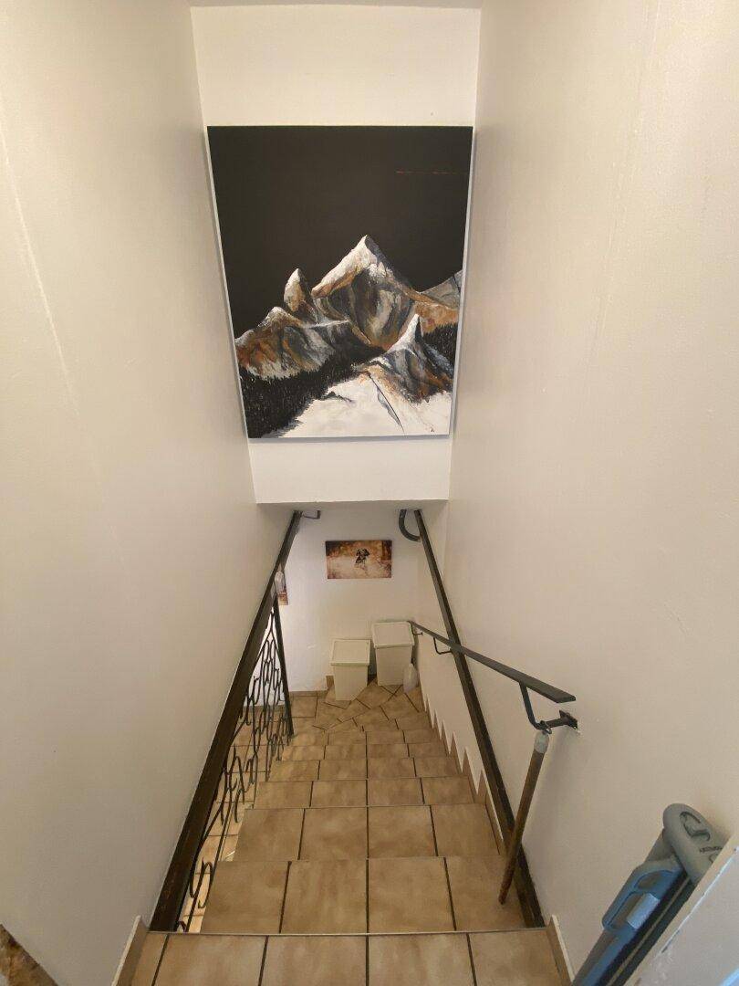 Gefliester Treppenabgang in den unteren Bereich des Hauses mit Wanddekoration.