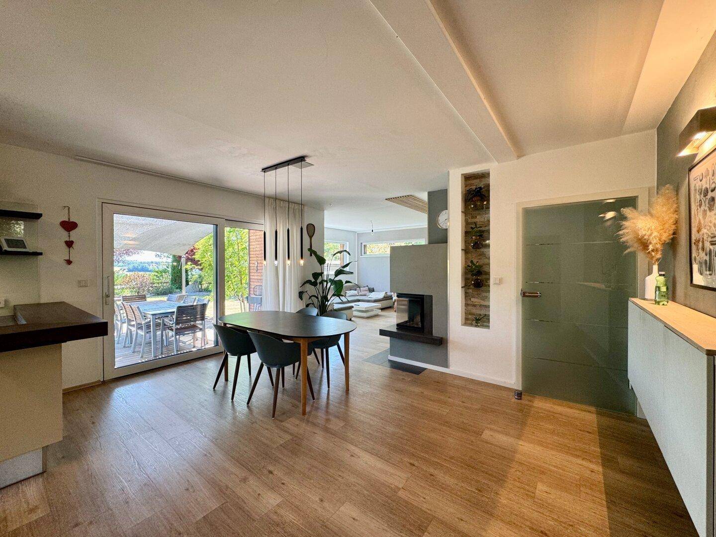 Offener Wohn- und Essbereich mit Holzboden, Kamin und direktem Zugang zur sonnigen Terrasse.