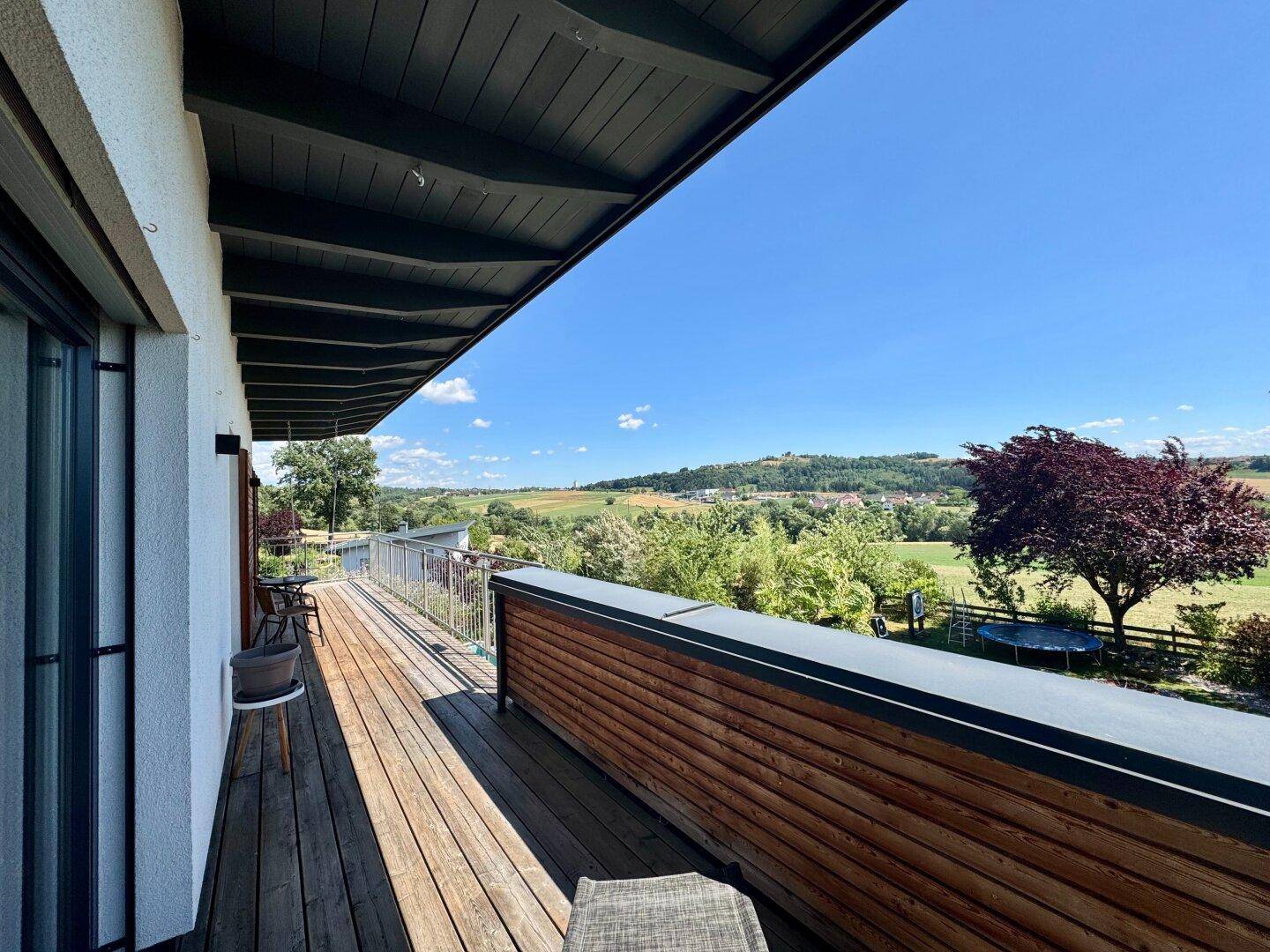 Langer Balkon mit Holzboden und Holzverkleidung bietet einen schönen Ausblick auf den Garten.