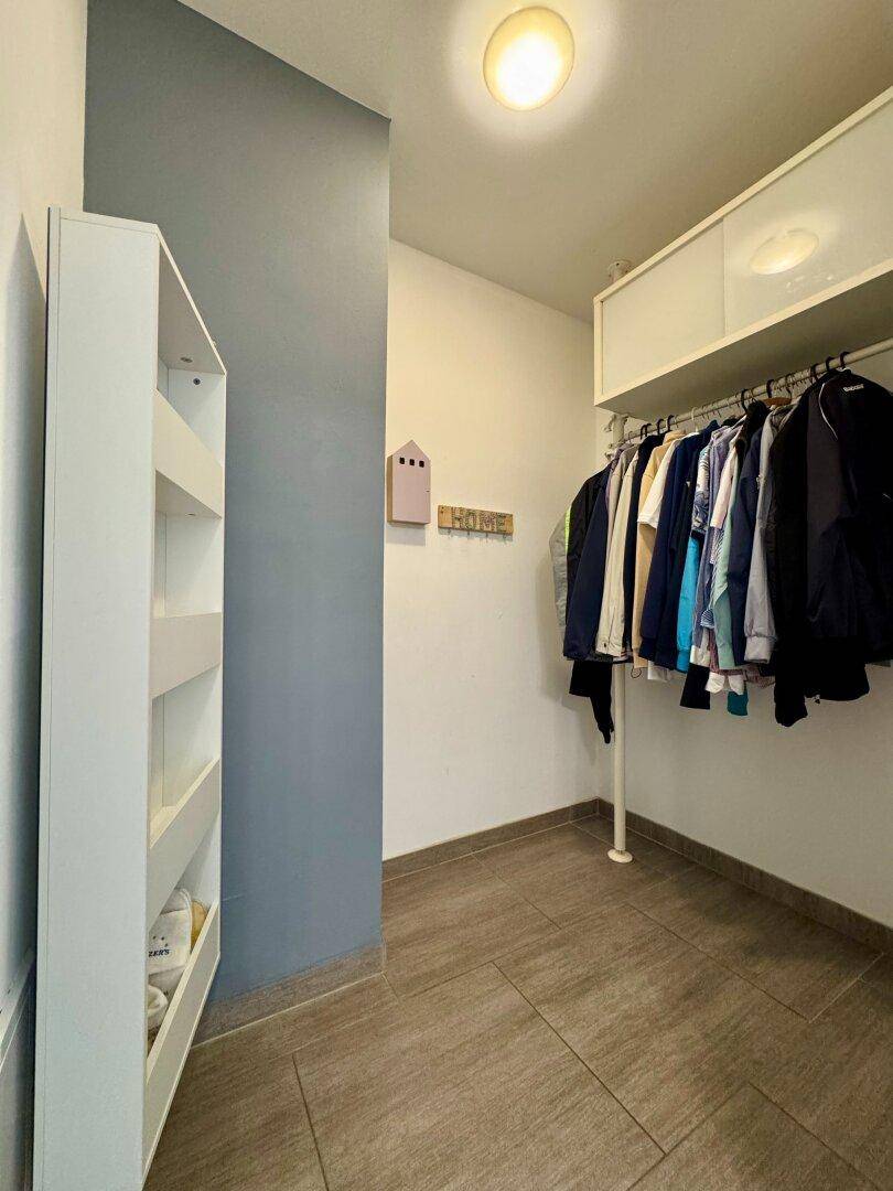 Praktischer Abstellraum oder begehbarer Kleiderschrank mit Kleiderstange und Regalen.