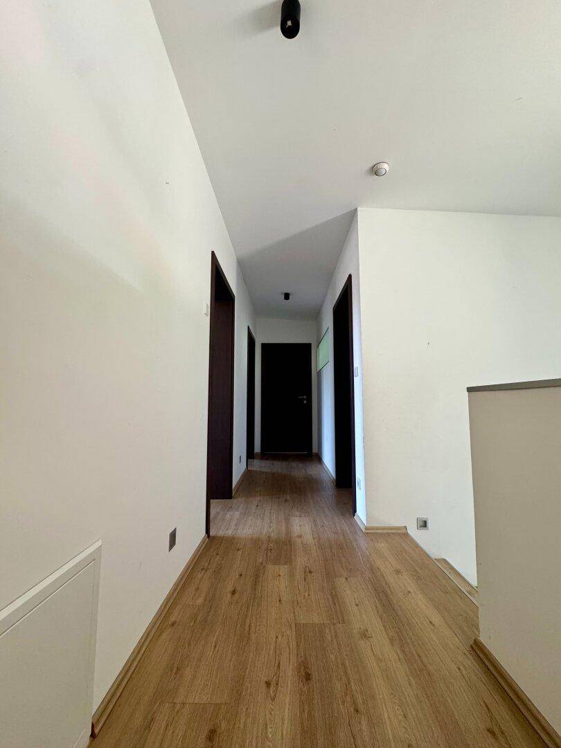 Langer, heller Flur mit Holzfußboden und mehreren Türen, der zu den Zimmern führt.