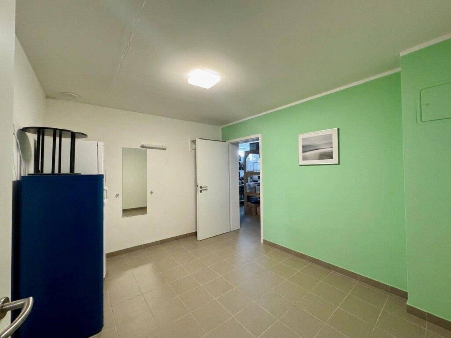 Vielseitiger Raum mit Fliesenboden und grüner Wand, ideal als Hauswirtschaftsraum.