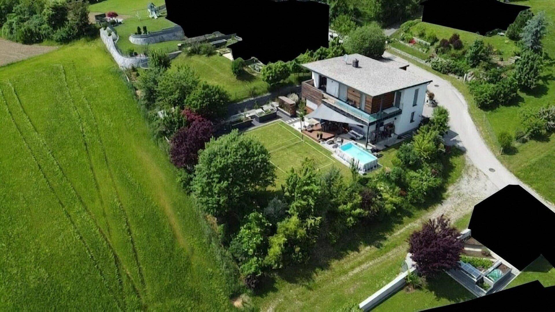 Luftaufnahme des modernen Hauses mit großem Garten, Pool und Tennisplatz in ländlicher Umgebung.