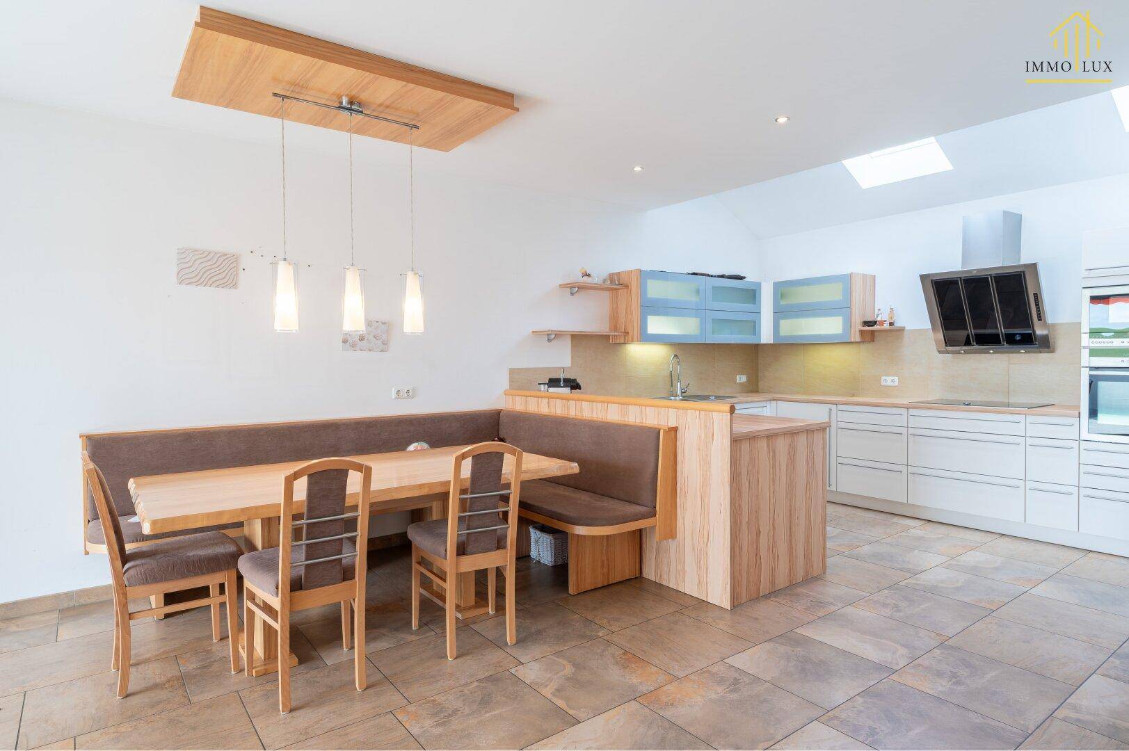Helle Wohnküche mit Holztisch, Eckbank und modernen Einbauschränken.