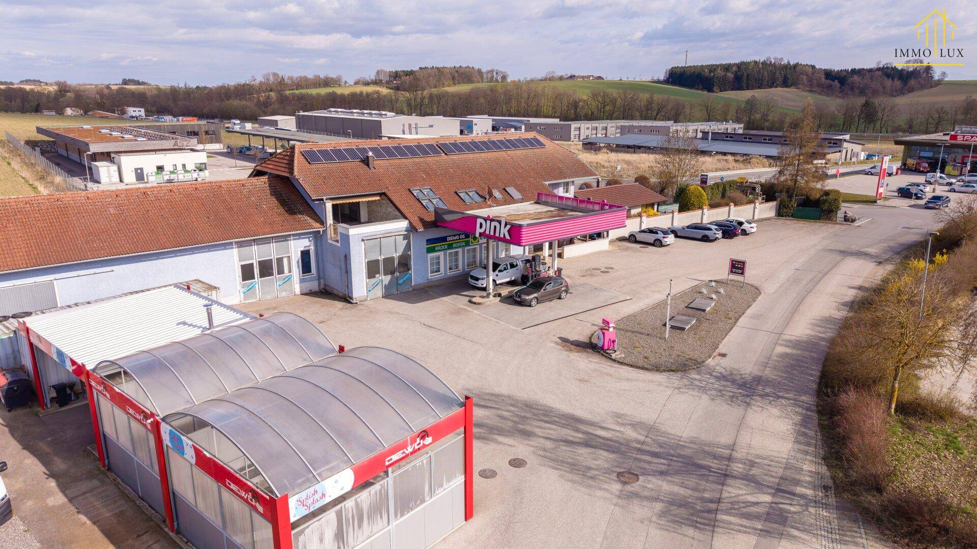 Luftaufnahme des Gewerbeobjekts mit Tankstelle, Waschanlage und Solaranlage bei Tageslicht.