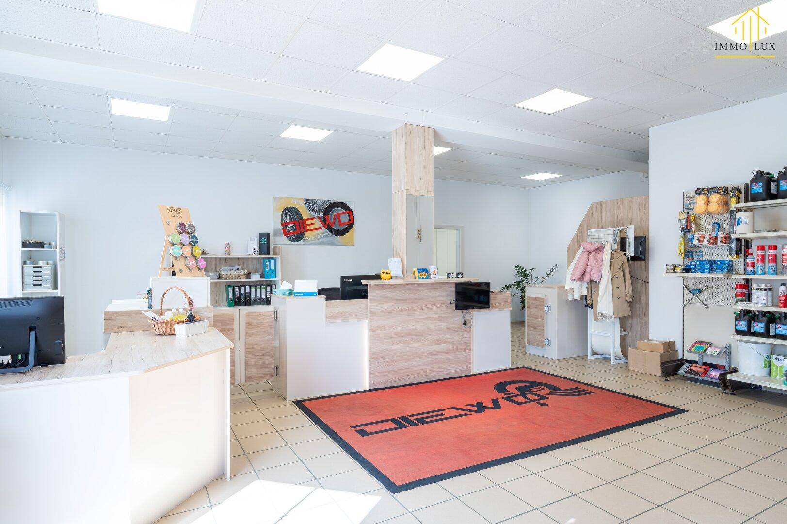 Heller Empfangsbereich mit Verkaufstheke, Fliesenboden und modernen Deckenleuchten.