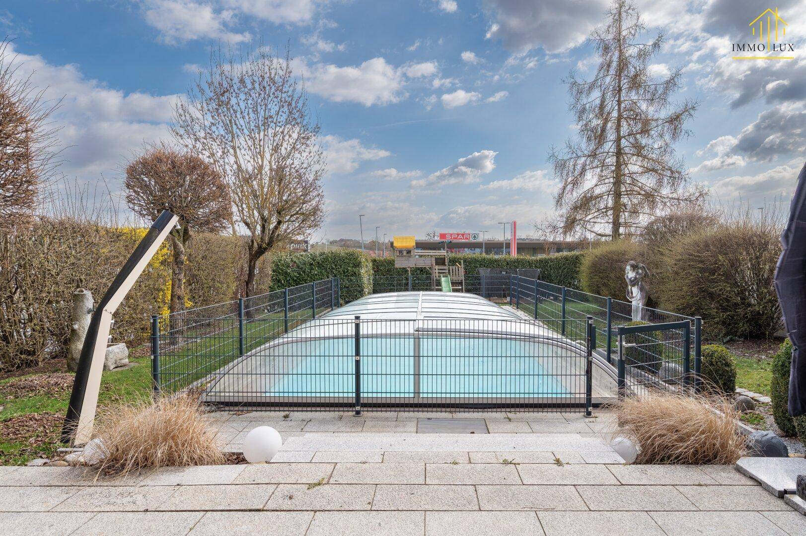Gepflegter Gartenbereich mit umzäuntem Pool und Steinplattenweg.