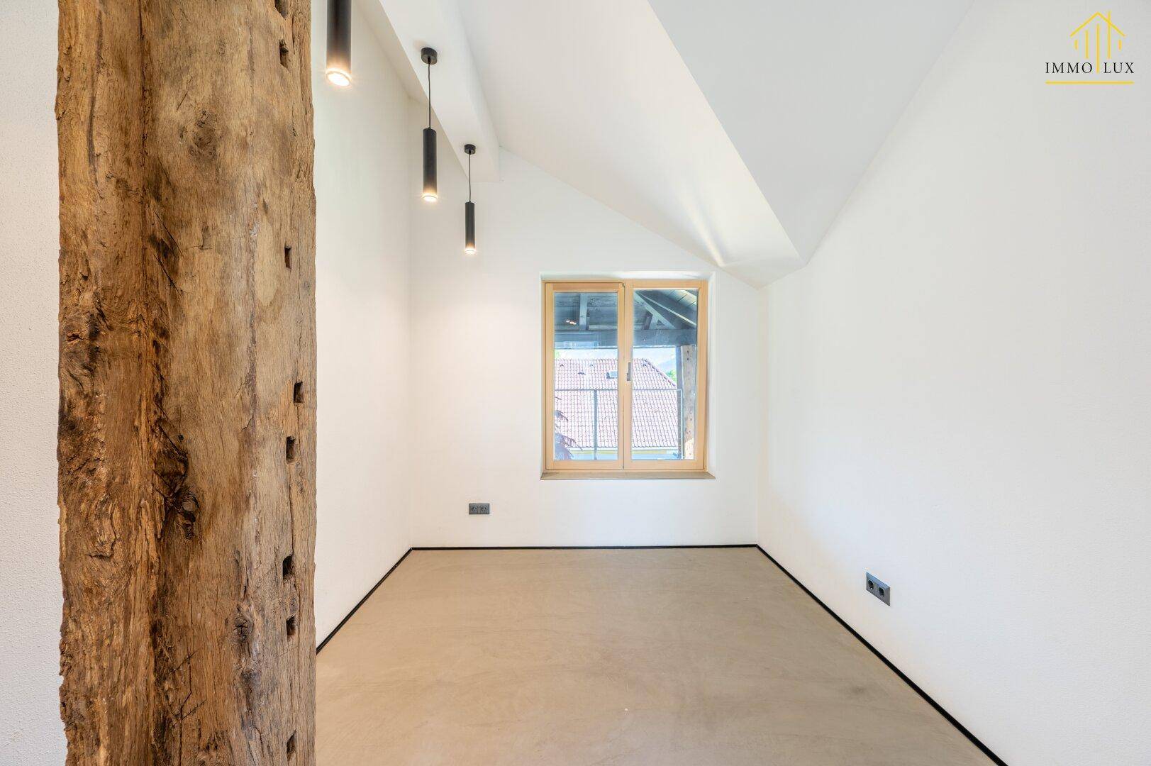 Geräumiges Zimmer mit Holzbalken, Fenster und minimalistischer Gestaltung.