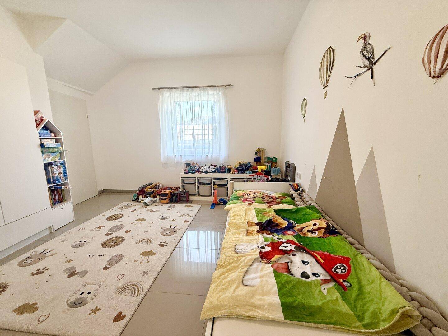 Geräumiges Kinderzimmer mit viel Platz zum Spielen, einem gemütlichen Bett und kindgerechter Dekoration.