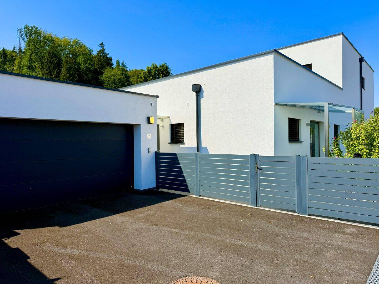 Moderne Hausfassade mit integrierter Garage und stilvollem Zaun, der Privatsphäre bietet.