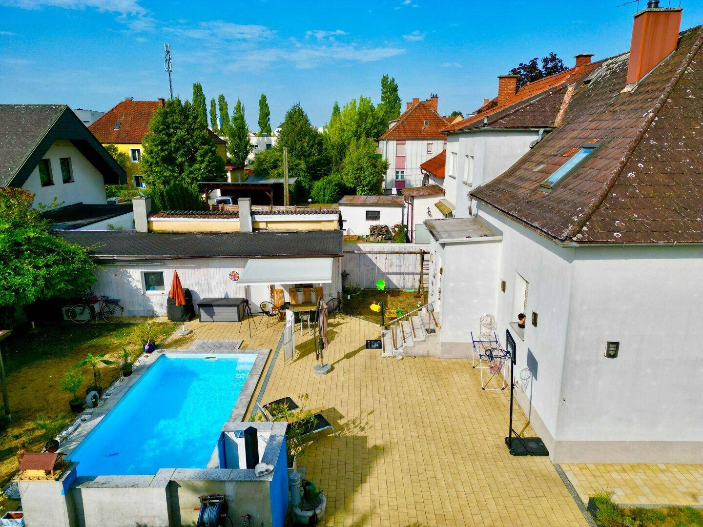 Luftaufnahme des Anwesens mit Poolbereich, Nebengebäuden und umliegender Wohnbebauung.