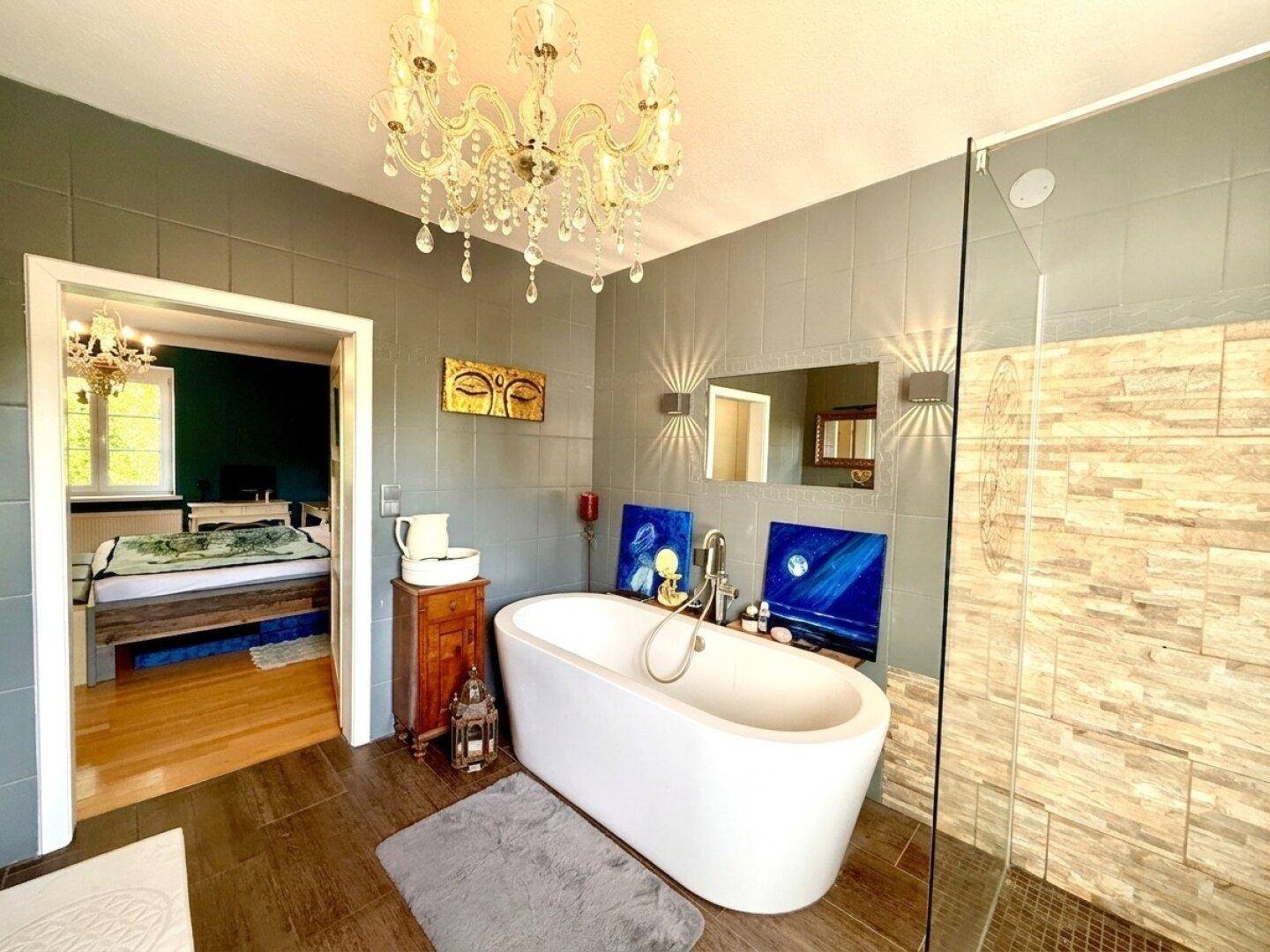 Modernes Badezimmer mit freistehender Badewanne, begehbarer Dusche und Blick ins Schlafzimmer.