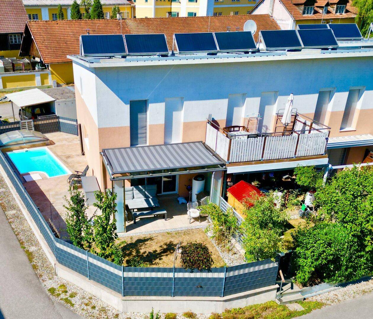 Luftaufnahme des modernen Hauses mit Pool, Garten, Balkon und Solaranlage auf dem Dach.