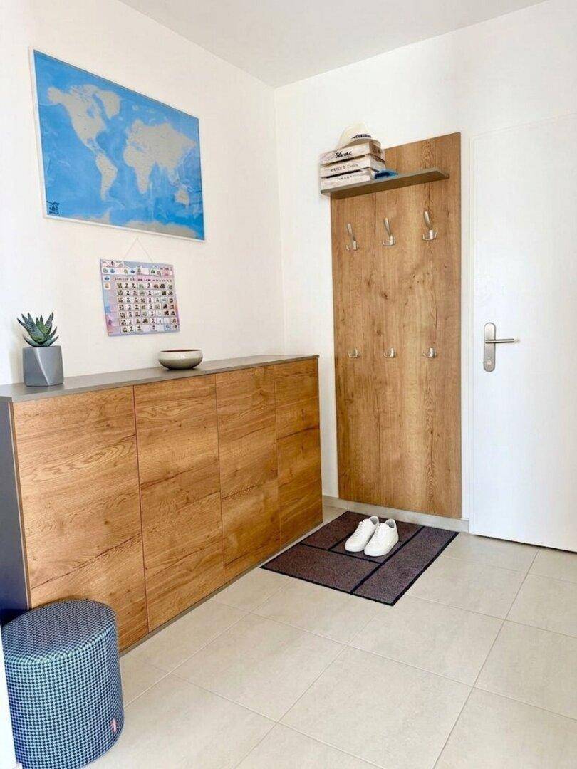 Heller Eingangsbereich mit modernem Holzschrank, Garderobe und Fliesenboden.