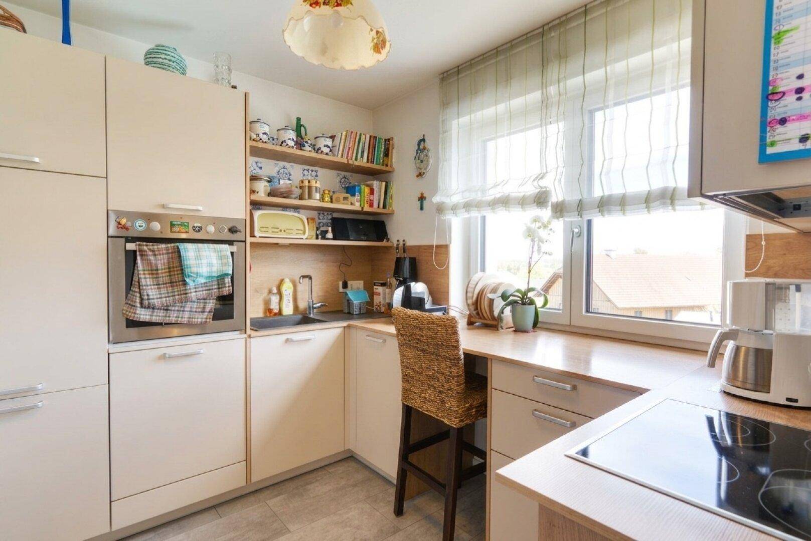 Gemütliche Küche mit hellen Einbauschränken, integriertem Backofen und Fenster mit Ausblick.