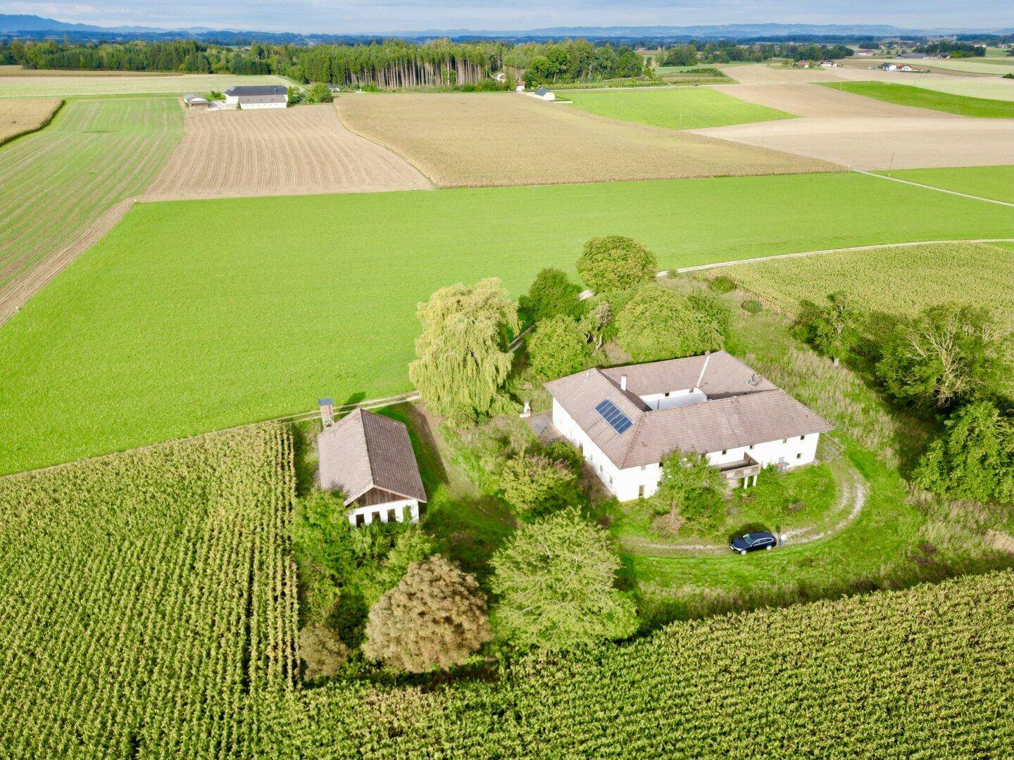 Panoramablick aus der Luft auf das Anwesen, eingebettet in weite grüne Felder und ländliche Umgebung.