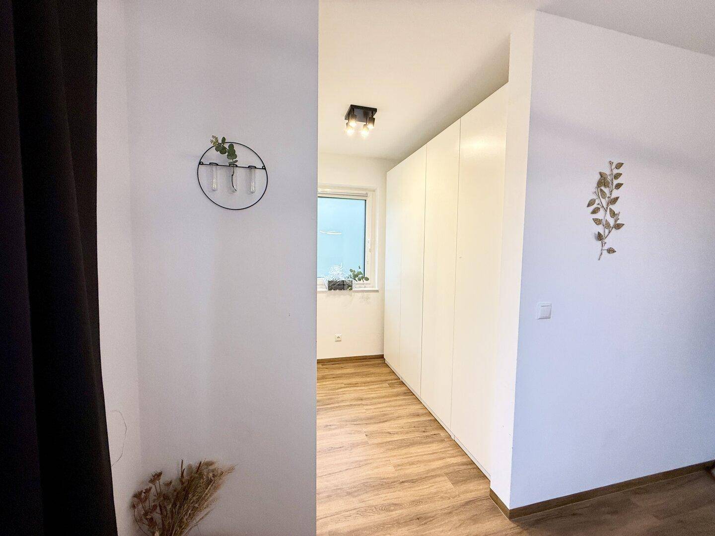 Heller Flur mit Einbauschränken und Fenster, bietet praktischen Stauraum.