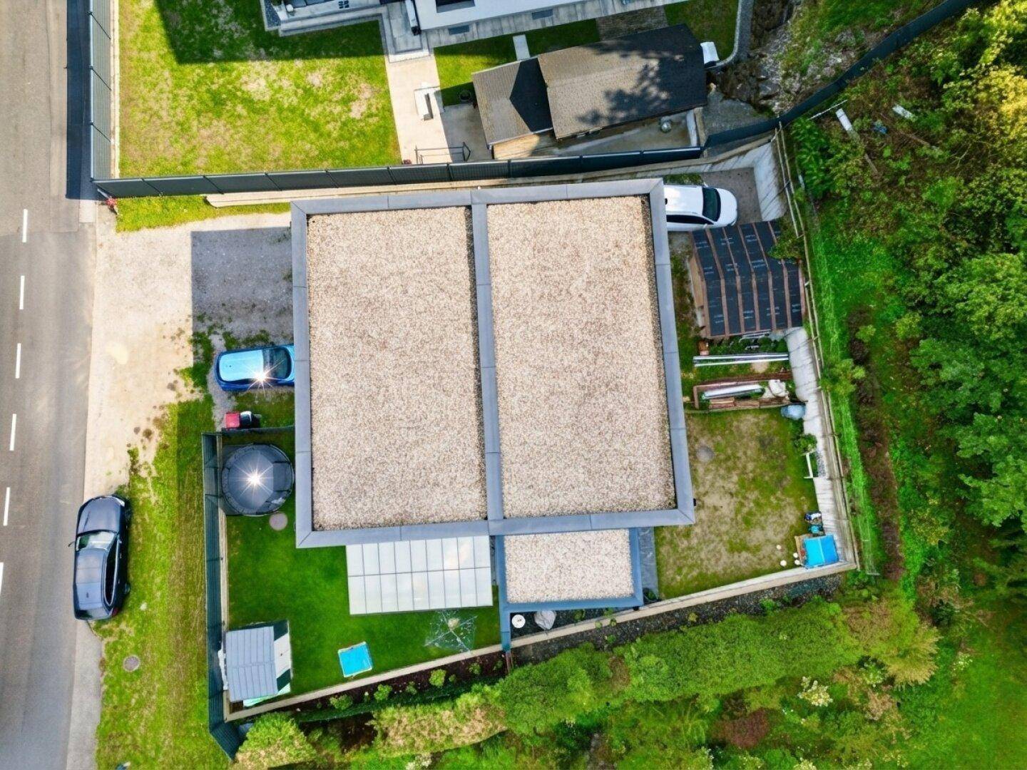 Luftaufnahme des modernen Hauses mit Flachdach und umliegendem Grundstück.