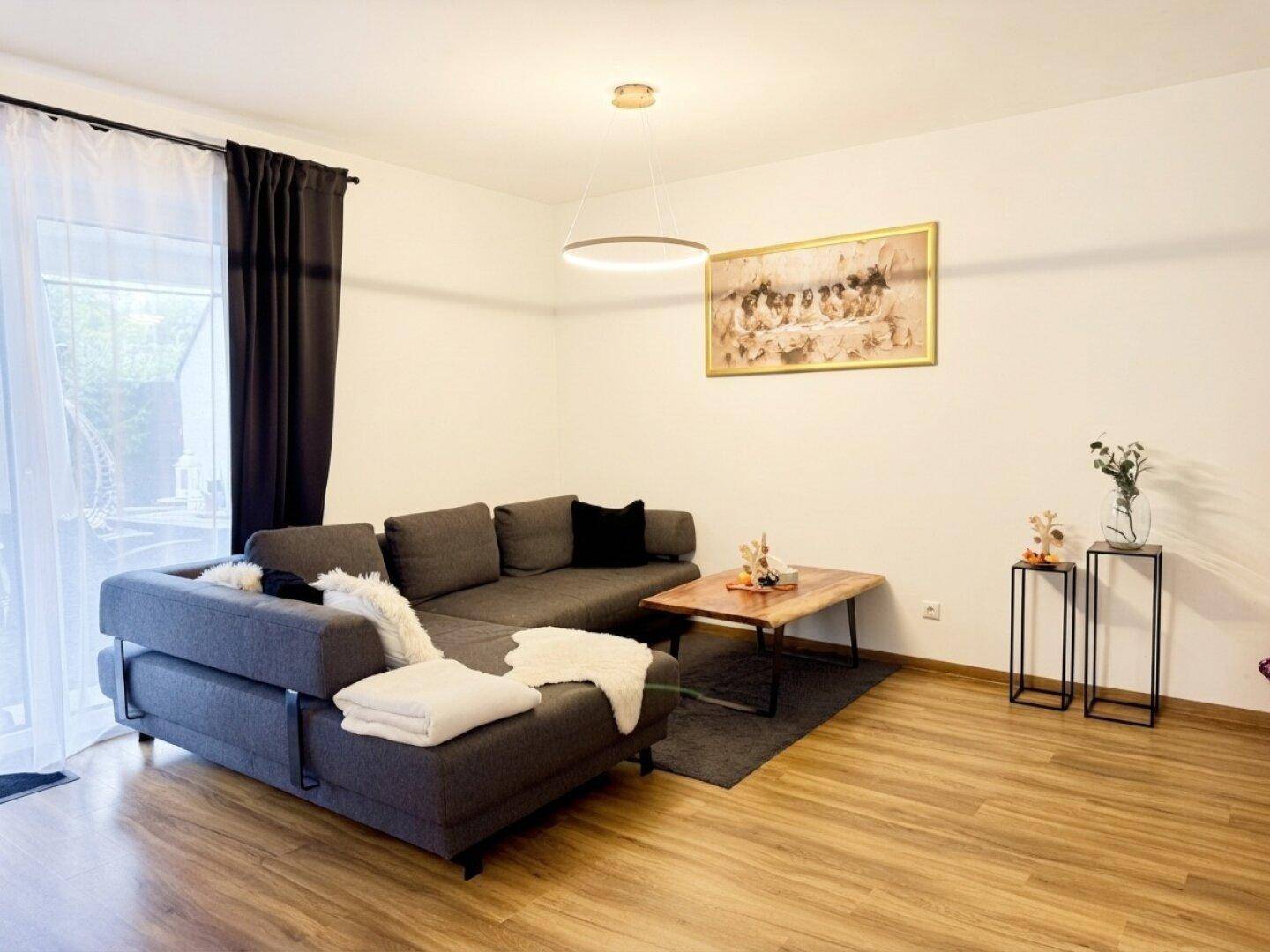 Gemütliches Wohnzimmer mit großem Ecksofa, Holztisch und Zugang zum Außenbereich.