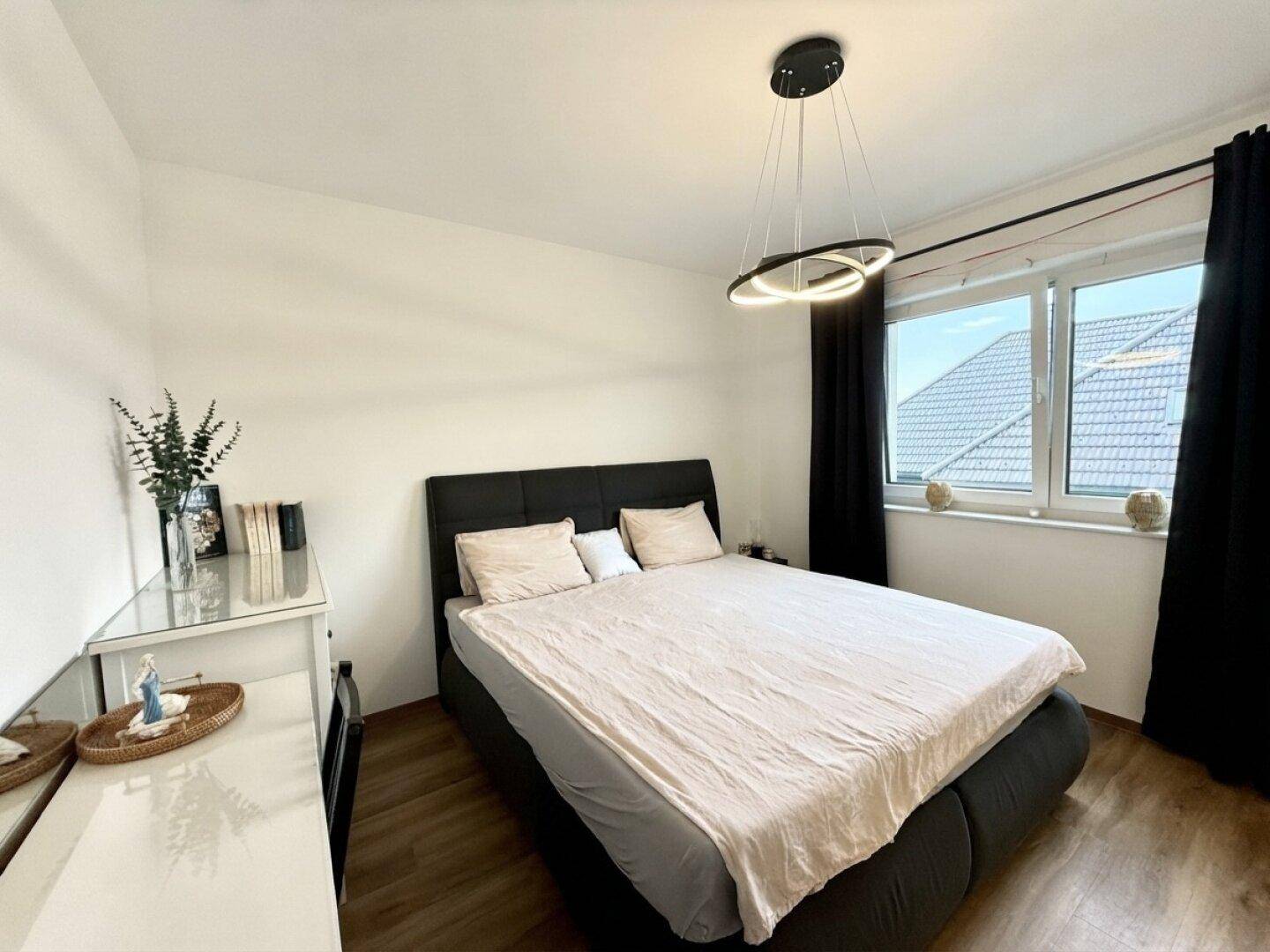 Gemütliches Schlafzimmer mit Doppelbett, Laminatboden und Fenster mit Blick ins Grüne.